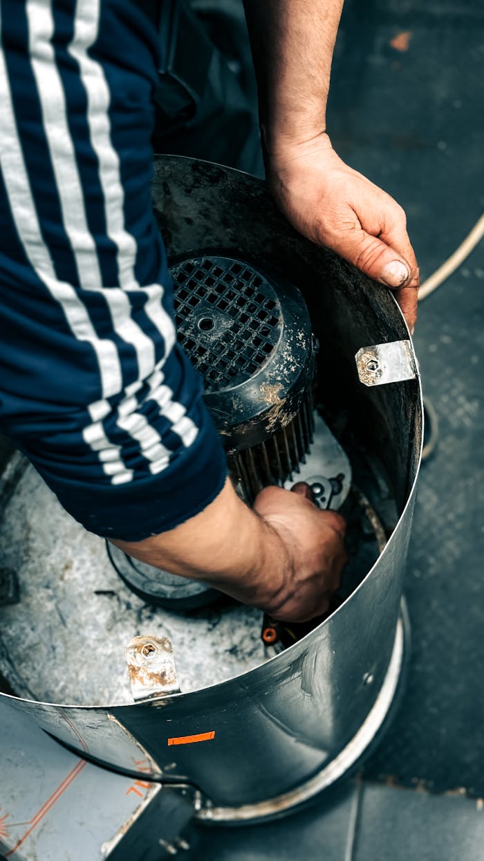 Close-up of hands repairing a motor inside industrial machinery. Technical repair process.